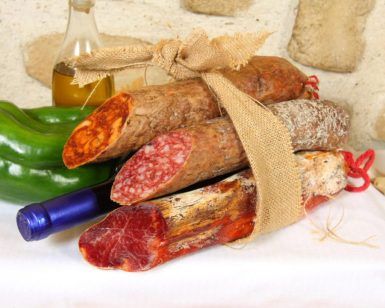 Un paquete de arpillera con una variedad de embutidos capturados captura el encanto rústico del Cercado de la Alpujarra, mientras que el pimiento verde, el ajo, el aceite de oliva y el vino evocan una experiencia de Menú a la carta en el Cercado de la Alpujarra. - ForTwo - Planes para parejas