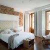Experimente el encanto de Eric Vökel Boutique Apartments en un dormitorio moderno con una pared con acento de ladrillo, ventanas grandes, una cama blanca impecable, pisos de madera cálidos y muebles minimalistas que crean un ambiente sereno. - ForTwo - Planes para parejas