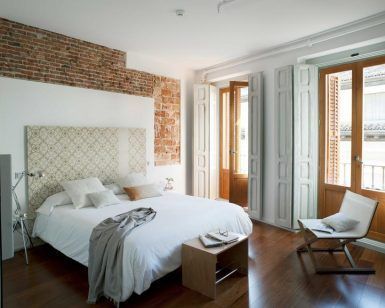 Experimente el encanto de Eric Vökel Boutique Apartments en un dormitorio moderno con una pared con acento de ladrillo, ventanas grandes, una cama blanca impecable, pisos de madera cálidos y muebles minimalistas que crean un ambiente sereno. - ForTwo - Planes para parejas
