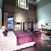 Descubra la elegancia de una habitación en el Hotel Eurostars Sevilla Boutique, equipada con una gran cama, detalles en morado, una decoración sofisticada y una impresionante vidriera. - ForTwo - Planes para parejas