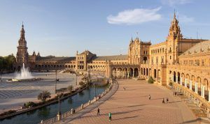 Únete al "Tour Gratuito a pie por Sevilla" en la Plaza de España para disfrutar del vibrante ambiente sevillano. Admira su emblemático edificio curvo y su fuente central mientras paseas con locales y turistas en un día soleado. - ForTwo - Planes para parejas