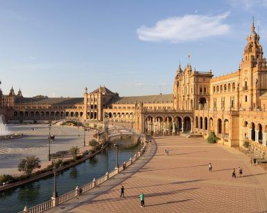 Únete al "Tour Gratuito a pie por Sevilla" en la Plaza de España para disfrutar del vibrante ambiente sevillano. Admira su emblemático edificio curvo y su fuente central mientras paseas con locales y turistas en un día soleado. - ForTwo - Planes para parejas