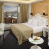 Disfrute de la elegancia del Hotel Gran Meliá Colón Sevilla con una lujosa cama, vista al balcón y una acogedora sala de estar con una mesa decorada con vino y naranjas frescas para mejorar su estadía. - ForTwo - Planes para parejas