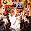 Tres mujeres saborean batidos en el Hard Rock Café Barcelona, sonriendo y charlando en medio de un ambiente bellamente decorado. - ForTwo - Planes para parejas