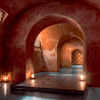 Un pasillo arqueado con iluminación tenue que recuerda a la Experiencia Hammam Tradicional - Baño Turco en Madrid, con paredes estampadas y linternas que proyectan cálidos reflejos de luz en el suelo. - ForTwo - Planes para parejas