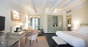 Disfrute de una espaciosa habitación en el Hotel Hospes Las Casas del Rey de Baeza, Sevilla, con una cama grande, cómodos sillones y un escritorio. Relájese viendo la televisión o admire las vistas desde el balcón a través de las puertas dobles en el encantador corazón de la ciudad. - ForTwo - Planes para parejas