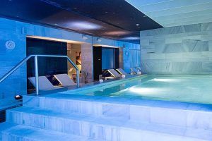 El Spa del Hospes Palacio de los Patos en Granada cuenta con una piscina cubierta con tumbonas, una relajante iluminación azul y un interior de mármol para un ambiente sereno. - ForTwo - Planes para parejas