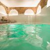 Descubra el Spa Privado con Comida o Cena en el Hospes Puerta de Alcalá, Madrid, con una piscina interior de agua turquesa y arcos de ladrillo. Lujosas tumbonas y velas titilantes crean un ambiente tranquilo en este exclusivo refugio. - ForTwo - Planes para parejas