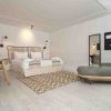 Ubicada en el Hotel 7 Islas Madrid, esta habitación minimalista incluye una cómoda cama, un televisor montado en la pared, un escritorio elegante, un cómodo sillón y una elegante alfombra sobre un piso de madera clara. - ForTwo - Planes para parejas