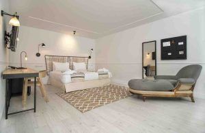 Ubicada en el Hotel 7 Islas Madrid, esta habitación minimalista incluye una cómoda cama, un televisor montado en la pared, un escritorio elegante, un cómodo sillón y una elegante alfombra sobre un piso de madera clara. - ForTwo - Planes para parejas