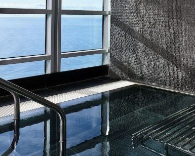 El Desayuno, Spa de Lujo y Masaje: La Experiencia Total en el Hotel Arts (Barcelona) cuenta con una piscina cubierta con mosaicos y barandillas metálicas, que ofrece impresionantes vistas al mar a través de grandes ventanales. - ForTwo - Planes para parejas