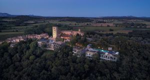Vista aérea del Hotel Castell d'Emporda (Girona) iluminado y estructuras cercanas enmarcadas en el paisaje rural al anochecer. - ForTwo - Planes para parejas