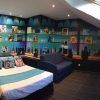 El elegante dormitorio imita una suite del Hotel Indiana (Madrid), con una lujosa cama, un sofá azul, arte mural vibrante, tragaluz y un televisor que muestra una escena de película, ofreciendo el ambiente elegante que esperarías en Madrid. - ForTwo - Planes para parejas