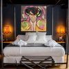 La habitación del vestíbulo del hotel Sevilla presenta una decoración moderna con una cama con dosel, arte abstracto vibrante y dos lámparas naranjas que iluminan las paredes oscuras, creando un ambiente acogedor. - ForTwo - Planes para parejas