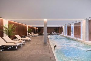 Relájese junto a la piscina interior del spa del Hotel Marina, Badalona, con tumbonas, iluminación tenue, toallas enrolladas y macetas. Disfrute de este ambiente tranquilo con nuestro exclusivo paquete de 60 minutos "Circuito Spa" y una exquisita comida en el Hotel Marina. - ForTwo - Planes para parejas