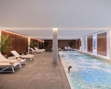 Relájese junto a la piscina interior del spa del Hotel Marina, Badalona, con tumbonas, iluminación tenue, toallas enrolladas y macetas. Disfrute de este ambiente tranquilo con nuestro exclusivo paquete de 60 minutos "Circuito Spa" y una exquisita comida en el Hotel Marina. - ForTwo - Planes para parejas