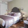 Descubra la elegancia del Hotel Palacete de Álamos Málaga: disfrute de una elegante habitación con una cama tamaño king, detalles en morado, cómodas sillas y un moderno baño abierto con una lujosa bañera para la combinación perfecta de comodidad y sofisticación. - ForTwo - Planes para parejas