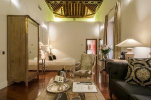 Disfrute de un retiro de lujo en el Hotel Palacio de Pinello Sevilla, donde el dormitorio cuenta con un techo de madera, muebles elegantes, una cama acogedora y una iluminación suave en el corazón de Sevilla. - ForTwo - Planes para parejas
