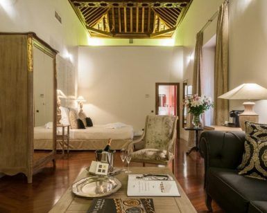 Disfrute de un retiro de lujo en el Hotel Palacio de Pinello Sevilla, donde el dormitorio cuenta con un techo de madera, muebles elegantes, una cama acogedora y una iluminación suave en el corazón de Sevilla. - ForTwo - Planes para parejas