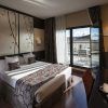 Moderna habitación en el Hotel Paseo Del Arte (Madrid) con una amplia cama y escritorio, además de una puerta de balcón abierta que revela una terraza con impresionantes vistas de la ciudad. - ForTwo - Planes para parejas