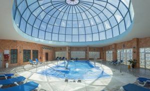 Escápese a nuestro Escapada en el Hotel & Spa Marbella Hills de 4 estrellas, con piscina cubierta con cúpula de cristal, tumbonas azules y ventanas con estampados que dejan entrar la luz del sol en cascada. Experimente una relajación inigualable en este lujoso oasis. - ForTwo - Planes para parejas
