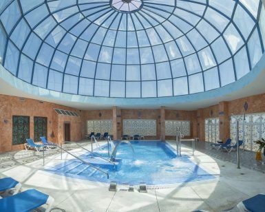 Escápese a nuestro Escapada en el Hotel & Spa Marbella Hills de 4 estrellas, con piscina cubierta con cúpula de cristal, tumbonas azules y ventanas con estampados que dejan entrar la luz del sol en cascada. Experimente una relajación inigualable en este lujoso oasis. - ForTwo - Planes para parejas