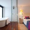 Una habitación del Hotel Vincci Selección Posada del Patio Málaga ofrece una bañera independiente, paredes texturizadas, una cama acogedora y almohadas vibrantes, combinando a la perfección estilo y comodidad. - ForTwo - Planes para parejas