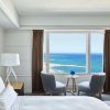 Disfrute de una tranquila estancia en el Hotel Arts (Barcelona) en una habitación con una acogedora cama, dos sillas y una pequeña mesa junto a un gran ventanal con impresionantes vistas al mar. - ForTwo - Planes para parejas