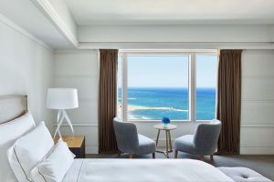 Disfrute de una tranquila estancia en el Hotel Arts (Barcelona) en una habitación con una acogedora cama, dos sillas y una pequeña mesa junto a un gran ventanal con impresionantes vistas al mar. - ForTwo - Planes para parejas