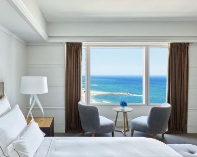 Disfrute de una tranquila estancia en el Hotel Arts (Barcelona) en una habitación con una acogedora cama, dos sillas y una pequeña mesa junto a un gran ventanal con impresionantes vistas al mar. - ForTwo - Planes para parejas