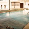 Una piscina cubierta con cascadas de agua y plantas en macetas ofrece un refugio sereno que recuerda la tranquilidad que se encuentra en el spa Día romántico del Hyatt Regency Barcelona, perfecto para relajarse antes de disfrutar de un delicioso almuerzo. - ForTwo - Planes para parejas