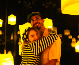 Una pareja se abraza y sonríe en medio del encantador resplandor de los faroles amarillos en la sala tenuemente iluminada de IKONO Madrid con sus Entradas para IKONO Madrid. - ForTwo - Planes para parejas