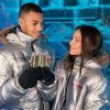 Dentro de ICEBARCELONA, una pareja con chaquetas plateadas choca sus copas, sus sonrisas iluminan el fondo helado de la experiencia Pack Romántico en ICEBARCELONA. - ForTwo - Planes para parejas