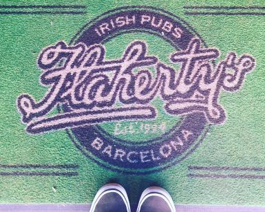 El felpudo verde presenta el logotipo de Brunch en Flaherty’s Irish Pub Barcelona, ideal para recibir a los invitados que aprecian un delicioso brunch, mientras que las zapatillas negras que se asoman en la parte inferior añaden un ambiente informal. - ForTwo - Planes para parejas