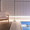 La acogedora piscina cubierta, con elegantes paredes de azulejos blancos, refleja el ambiente del Gran Hotel Inglés. Una silla de madera con cojines y un banco adornado con flores crean un remanso de paz ideal para relajarse después de disfrutar de un jacuzzi y un masaje privado en este distinguido hotel madrileño. - ForTwo - Planes para parejas