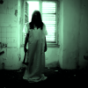 En la habitación oscura de Escape Room: La Casa Paranormal, una figura con un vestido largo sostiene siniestramente un hacha, recortada por la ventana: una escena perfecta para un desafío de escape. - ForTwo - Planes para parejas