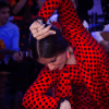 En medio de las animadas Cuevas del Sacromonte, el "Espectáculo Flamenco en las Cuevas del Sacromonte con Los Tarantos" muestra a una intensa bailaora de flamenco con un vestido de lunares rojos y negros, rodeada de músicos. - ForTwo - Planes para parejas
