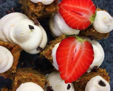 Primer plano de cuadrados de postre con remolinos de crema y fresas en rodajas en un plato azul oscuro, perfecto para un delicioso brunch en Brunch de comida local en MAAI Barcelona. - ForTwo - Planes para parejas