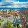 El antiguo acueducto de piedra se extiende majestuosamente por el paisaje urbano de Segovia, revelando la historia debajo del Alcázar de Segovia, presentado en "Ávila y Segovia: Excursión de un día desde Madrid con Entrada al Alcázar de Segovia", en medio de techos de terracota y un cielo parcialmente nublado. - ForTwo - Planes para parejas