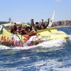 Un grupo disfruta de las vibrantes olas mientras corren por las aguas cercanas al impresionante paisaje urbano de Barcelona en "Surca las olas a toda velocidad en Chicken Boat en Barcelona". - ForTwo - Planes para parejas