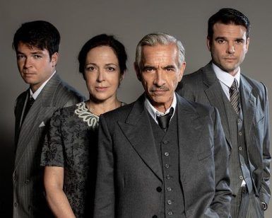 Cuatro personas vestidas con ropa formal vintage posan sobre un fondo gris, haciendo eco de una escena de "Muerte de un viajante - Teatro Infanta Isabel (Madrid)" y capturando el ambiente sofisticado del teatro. - ForTwo - Planes para parejas