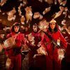 En el centro de Barcelona, tres figuras con monos rojos y máscaras sostienen rifles en medio de dinero flotando, creando una vívida escena del Museo de Cera de Barcelona. - ForTwo - Planes para parejas