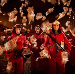 En el centro de Barcelona, tres figuras con monos rojos y máscaras sostienen rifles en medio de dinero flotando, creando una vívida escena del Museo de Cera de Barcelona. - ForTwo - Planes para parejas