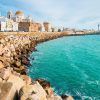 Experimente la belleza costera de Cádiz, España, con su impresionante catedral y sus encantadores edificios a lo largo de la rocosa costa. Disfrute de un cielo azul despejado y complemente su visita con un "Paseo en barco privado (Cádiz)" para disfrutar de una vista inolvidable desde el mar. - ForTwo - Planes para parejas