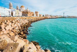 Experimente la belleza costera de Cádiz, España, con su impresionante catedral y sus encantadores edificios a lo largo de la rocosa costa. Disfrute de un cielo azul despejado y complemente su visita con un "Paseo en barco privado (Cádiz)" para disfrutar de una vista inolvidable desde el mar. - ForTwo - Planes para parejas