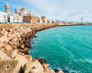Experimente la belleza costera de Cádiz, España, con su impresionante catedral y sus encantadores edificios a lo largo de la rocosa costa. Disfrute de un cielo azul despejado y complemente su visita con un "Paseo en barco privado (Cádiz)" para disfrutar de una vista inolvidable desde el mar. - ForTwo - Planes para parejas