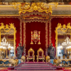 La gran sala del trono refleja el esplendor del Palacio Real de Madrid con sus paredes rojas, decoración dorada, dos tronos, grandes espejos, candelabros y estatuas de leones. Descubre esta elegancia con "Entradas para Madrid: Visita de día completo con entrada rápida al Museo del Prado y al Palacio Real. - ForTwo - Planes para parejas
