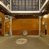 El interior del local Flamenco Los Olvidados, que recuerda al Palacio de los Olvidados, incluye una pared naranja, un escenario central, una fuente y columnas decorativas. Mejore su visita con Entradas sin colas al Palacio de los Olvidados para una entrada perfecta. - ForTwo - Planes para parejas