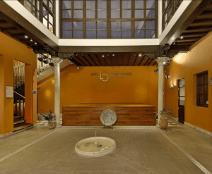 El interior del local Flamenco Los Olvidados, que recuerda al Palacio de los Olvidados, incluye una pared naranja, un escenario central, una fuente y columnas decorativas. Mejore su visita con Entradas sin colas al Palacio de los Olvidados para una entrada perfecta. - ForTwo - Planes para parejas