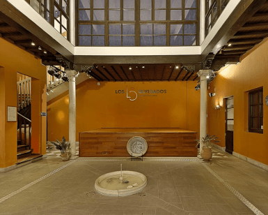 El interior del local Flamenco Los Olvidados, que recuerda al Palacio de los Olvidados, incluye una pared naranja, un escenario central, una fuente y columnas decorativas. Mejore su visita con Entradas sin colas al Palacio de los Olvidados para una entrada perfecta. - ForTwo - Planes para parejas
